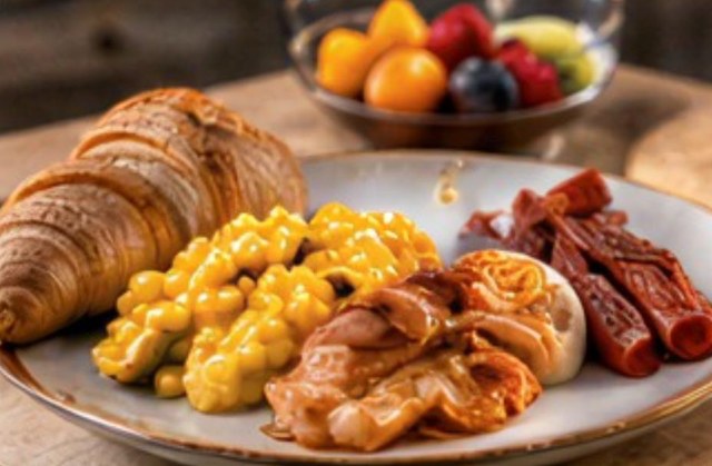 Classic-Frühstück mit Croissant, Rührei, Speck und Früchten